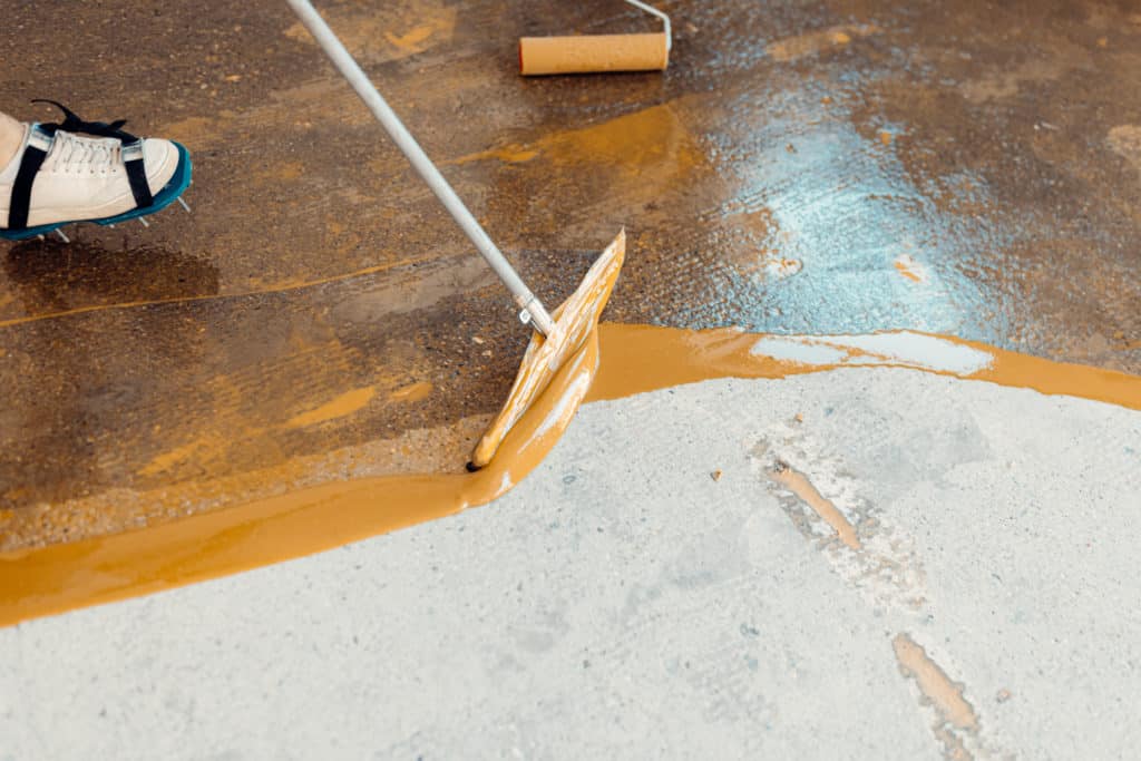 Applying epoxy floor coating with roller.