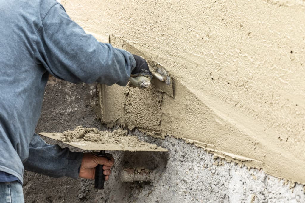 Worker applying stucco to exterior wall.