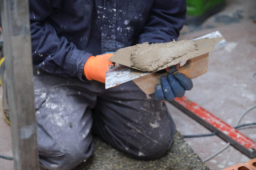 Worker holding trowel with wet cement.