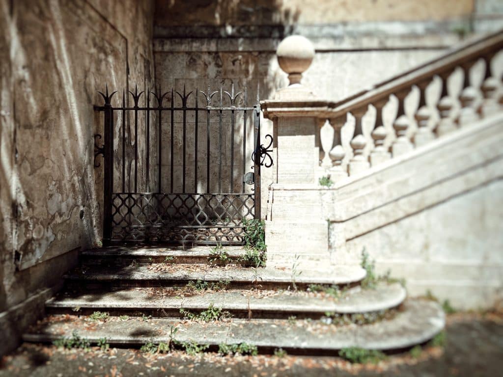 Old staircase with iron gate and weathered walls.