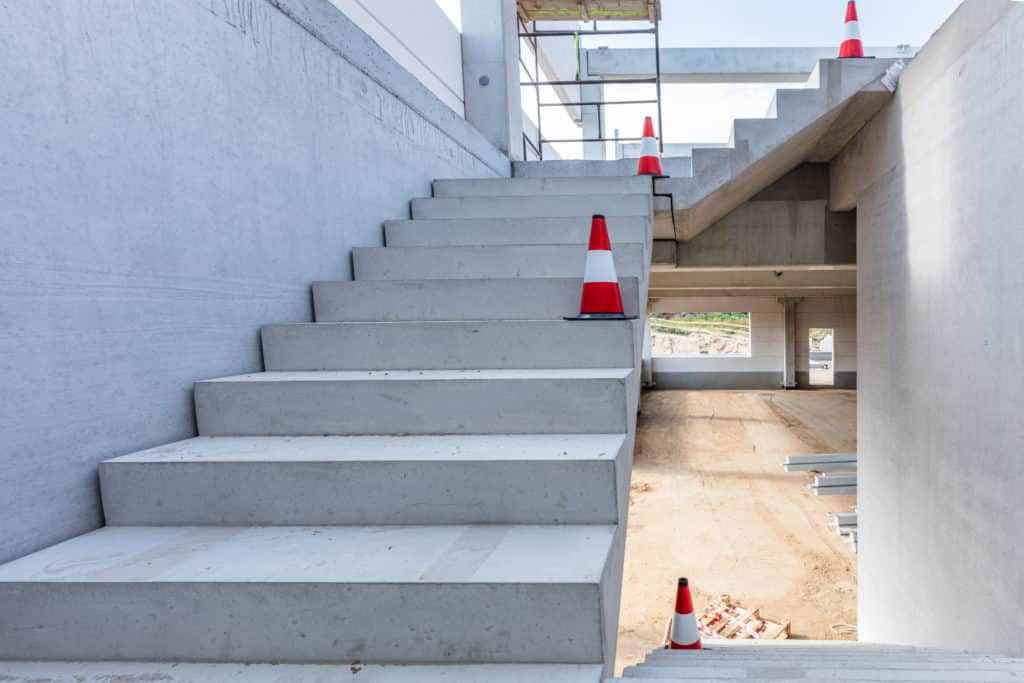 Concrete staircase with safety cones at construction site.