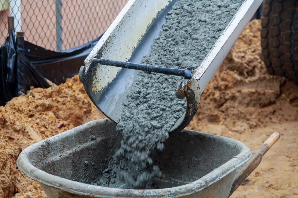 Pouring concrete into wheelbarrow at construction site.