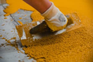 Applying yellow paint with trowel on concrete.