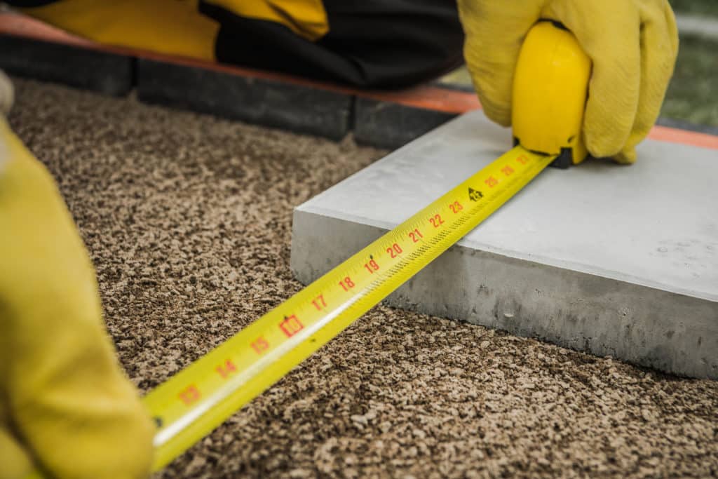 Worker measuring with tape measure on construction site.