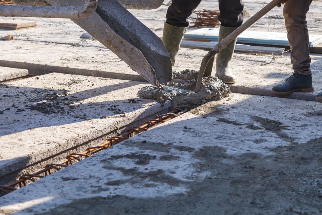 Workers pouring concrete at construction site.