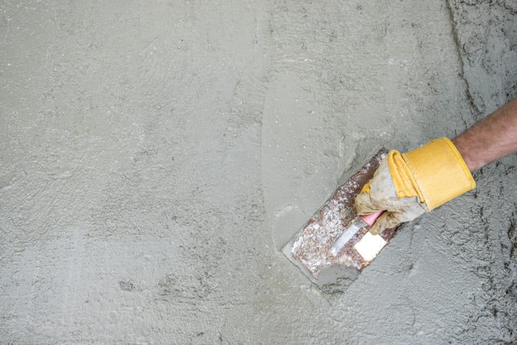 Worker smoothing concrete with trowel.