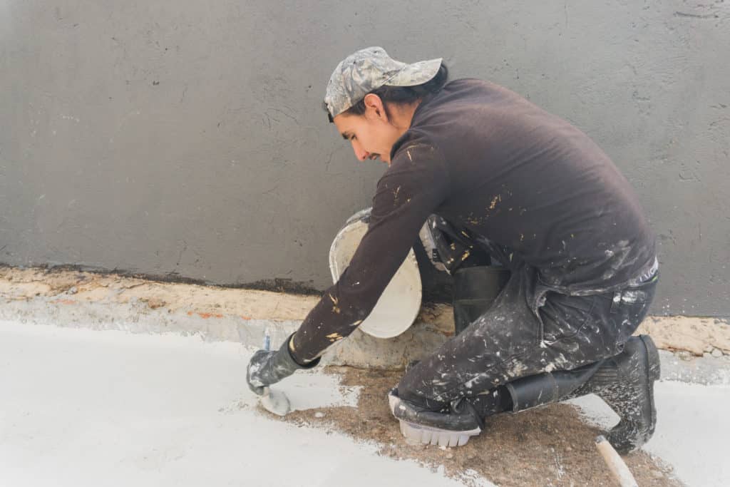 Worker applying cement on ground.