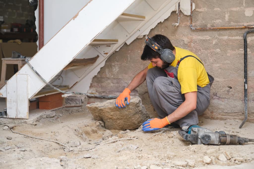 Construction worker examining rock at renovation site.