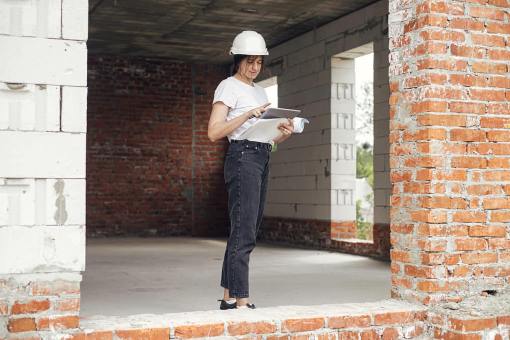 Female engineer inspecting construction site with plans