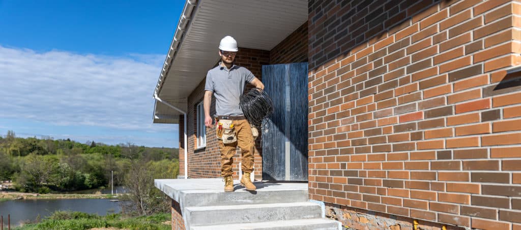 Electrician carrying cable spool at construction site.