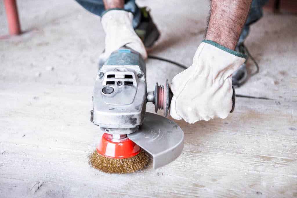 Worker using electric sander on wood floor.