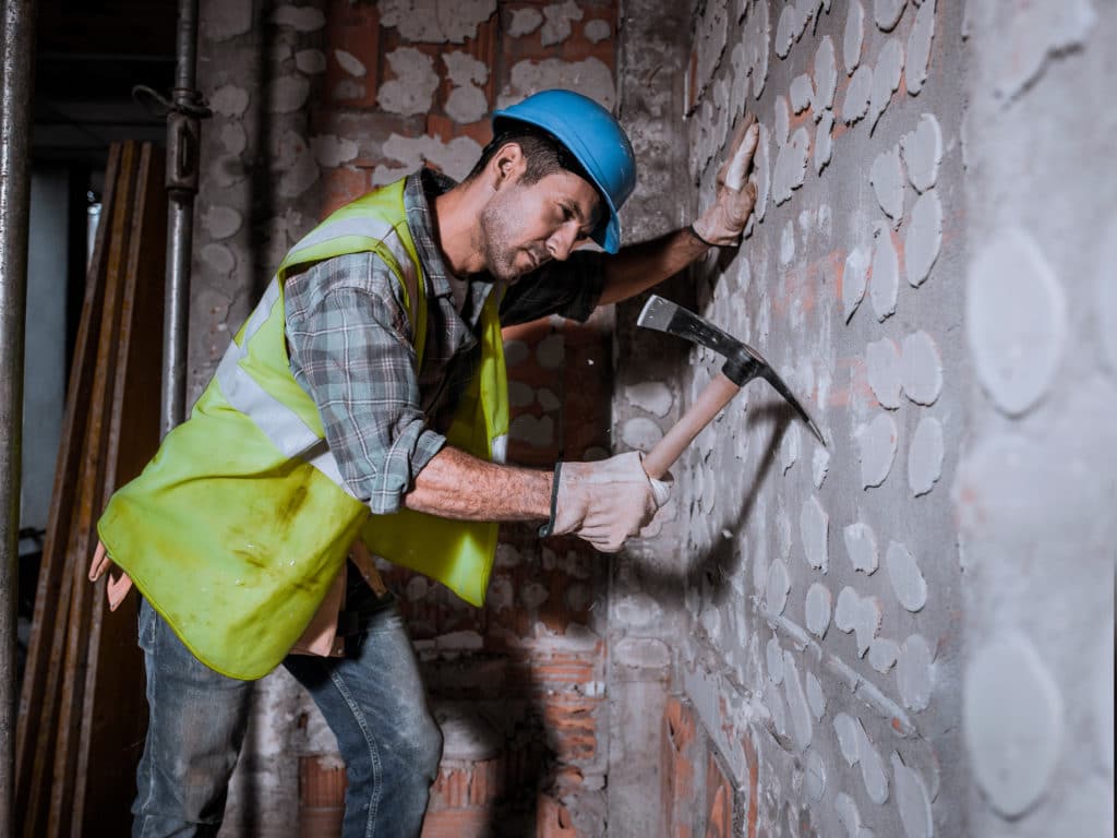 Construction worker chiseling wall on site.