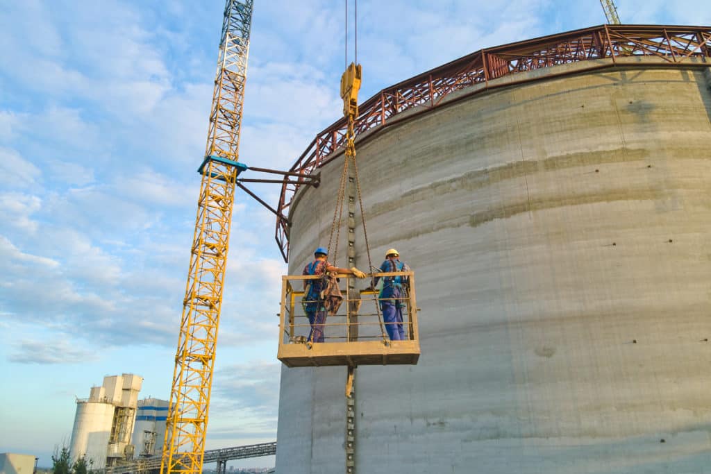 Workers on crane platform at industrial construction site