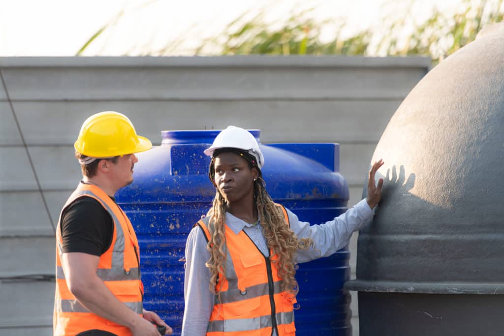 Two construction workers discussing near equipment outdoors.