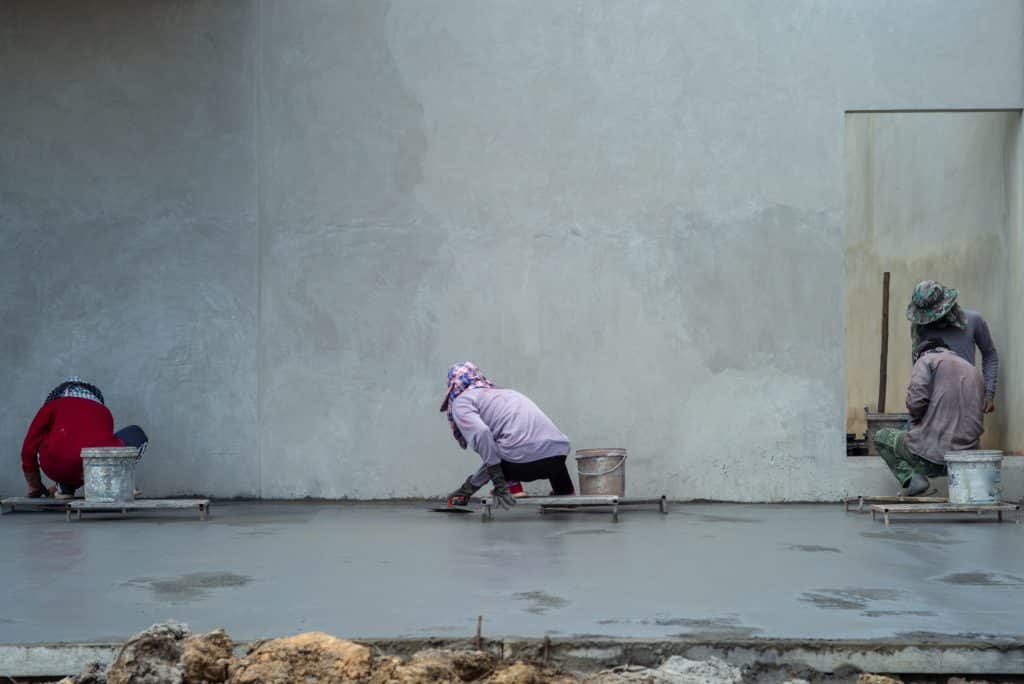 Workers smoothing concrete on construction site.