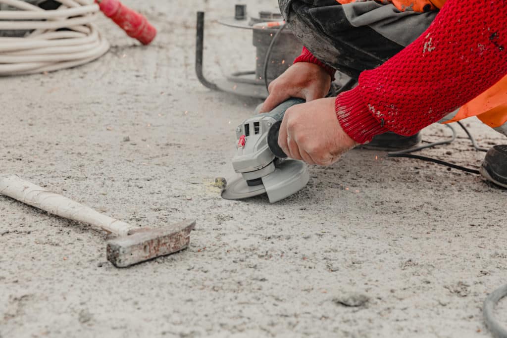 Worker using angle grinder on construction site.