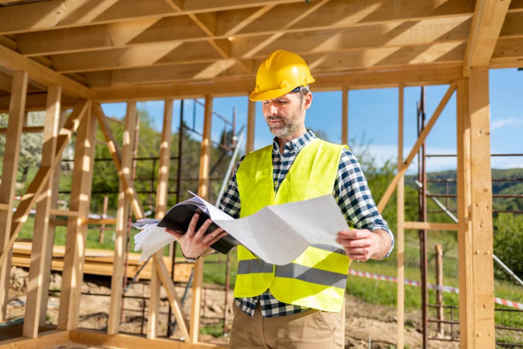 Construction worker reading plans on building site.