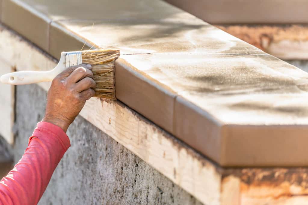 Person applying wood stain with brush.