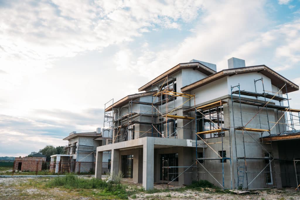 Houses under construction with scaffolding at sunset.