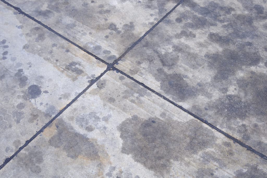 Stained concrete pavement tiles with cracks.