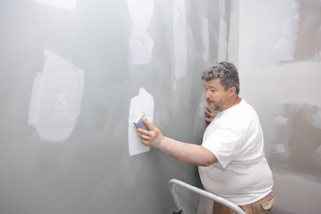 Man smoothing walls for painting.