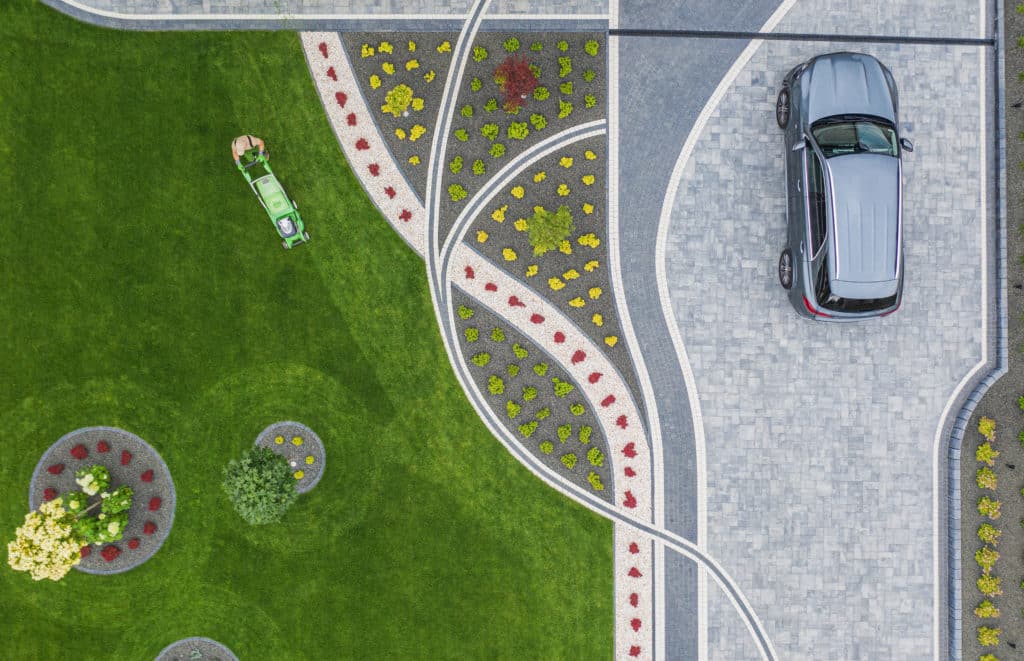 Aerial view of cars on patterned driveway with landscaping