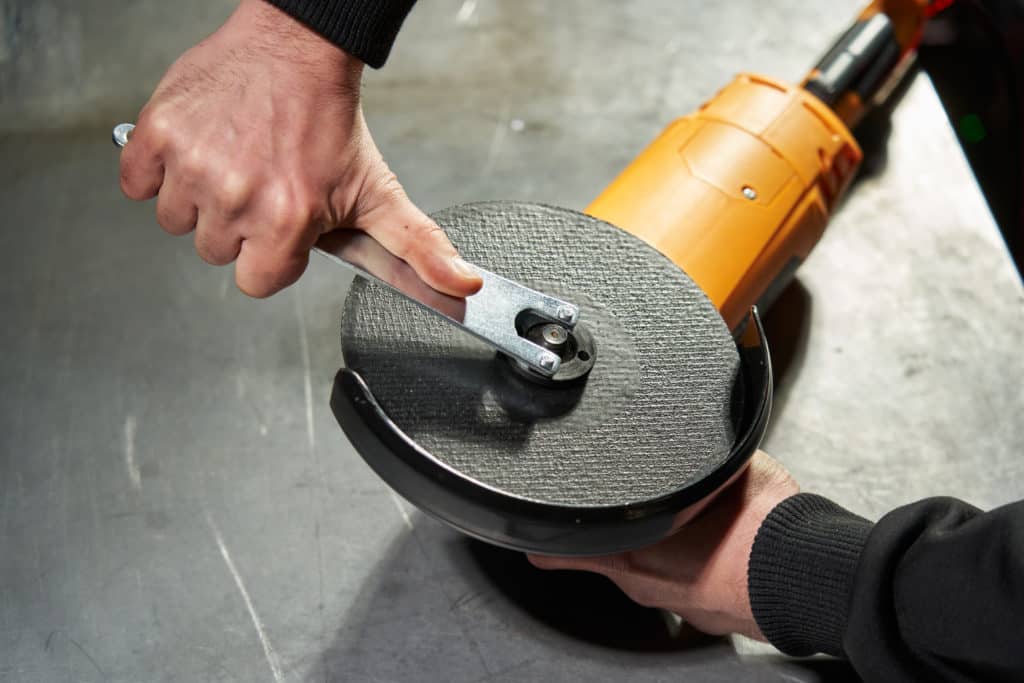 Person changing angle grinder cutting disc.