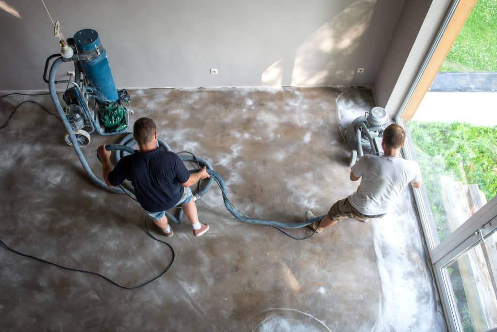 Workers polishing concrete floor indoors.