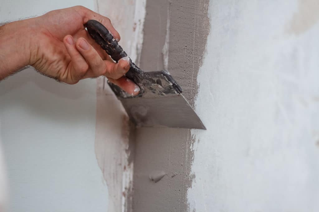 Applying plaster on wall with trowel