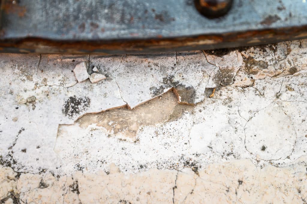 Rusty metal edge over cracked white stone surface.