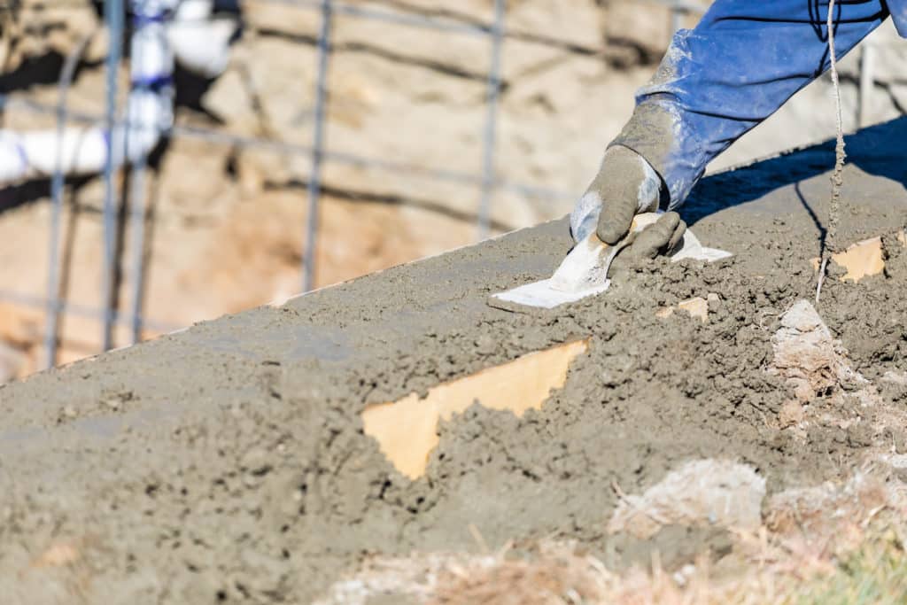 Worker smoothing concrete at construction site.