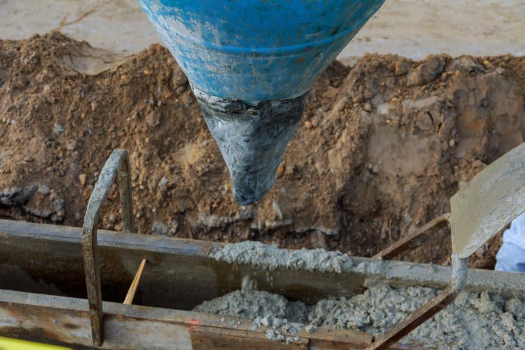 Concrete pouring from chute into foundation forms.