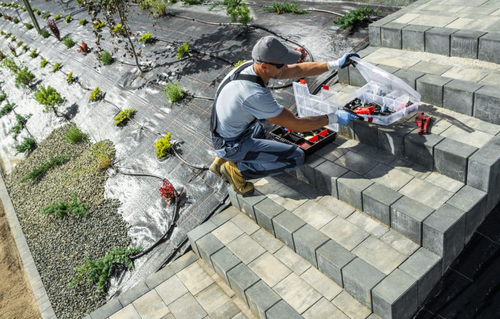 Worker installing irrigation system in garden.