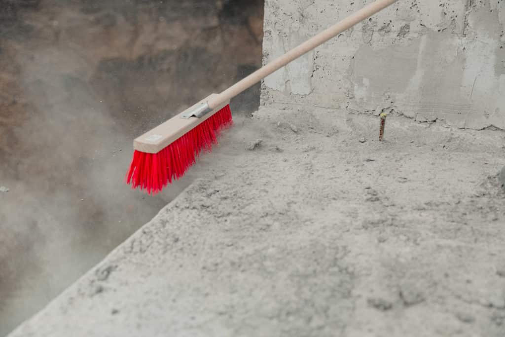 Broom sweeping dust on concrete surface.