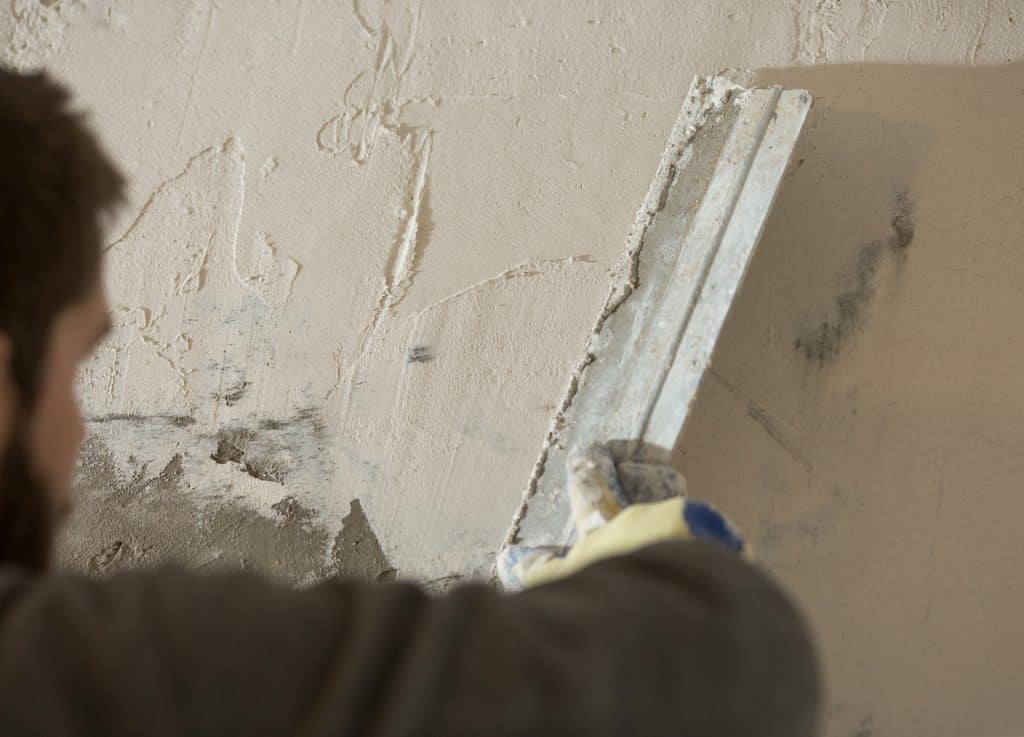 Person applying plaster on wall for repair.