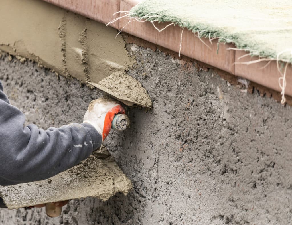 Worker applying stucco to exterior wall.