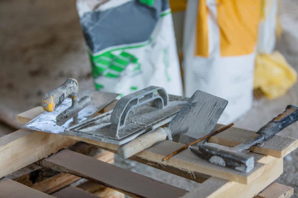 Masonry tools on a workbench with cement bags.