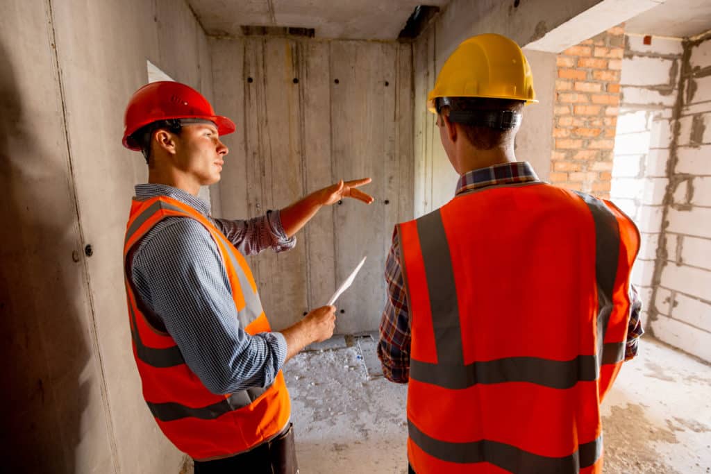 Construction workers discussing inside building site.