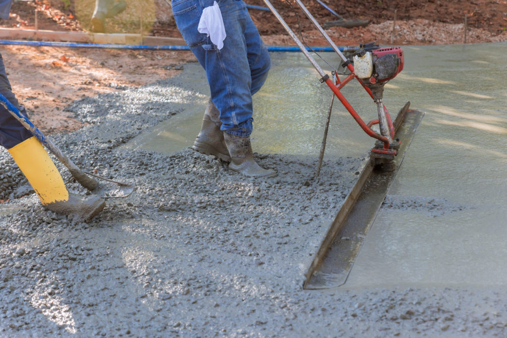 Workers smoothing concrete with trowel machine.