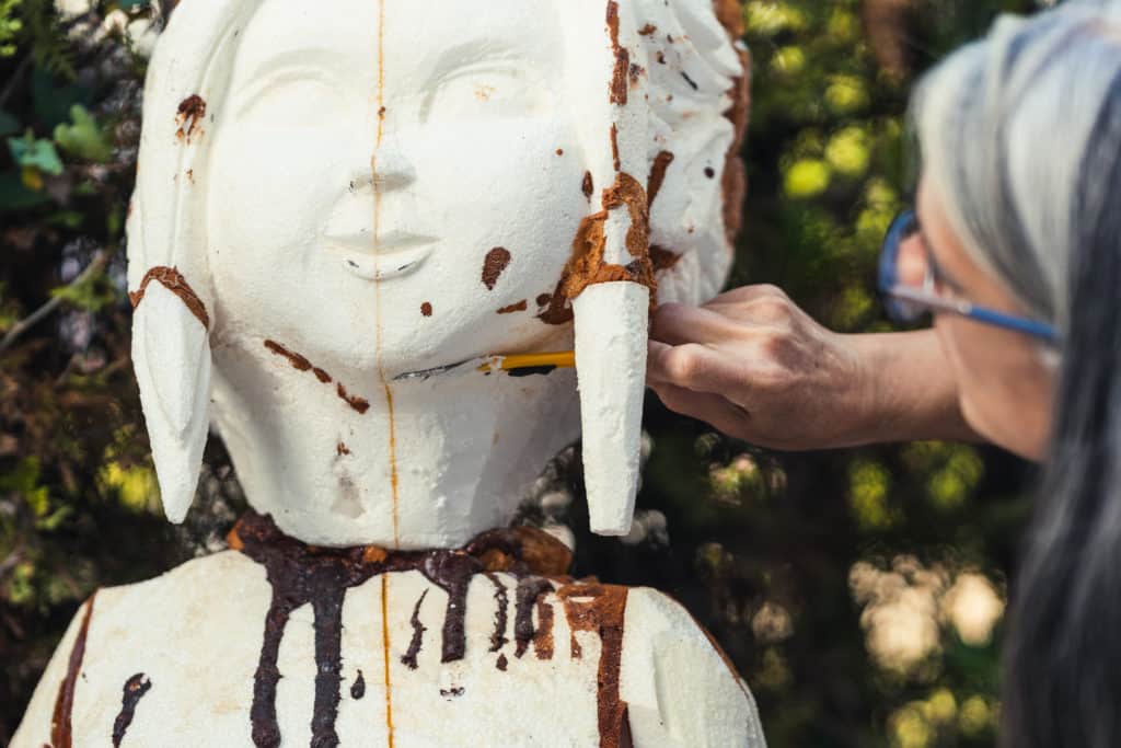 Person restoring rusted sculpture's face.