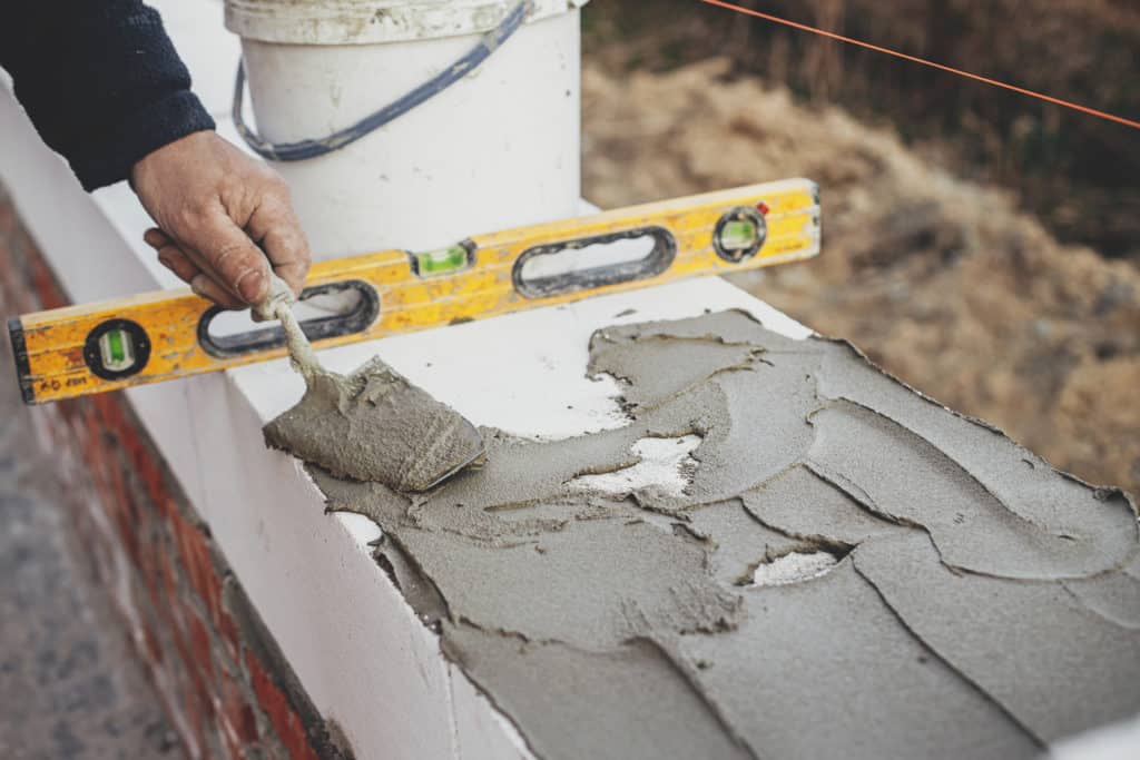 Worker using level on wet cement.