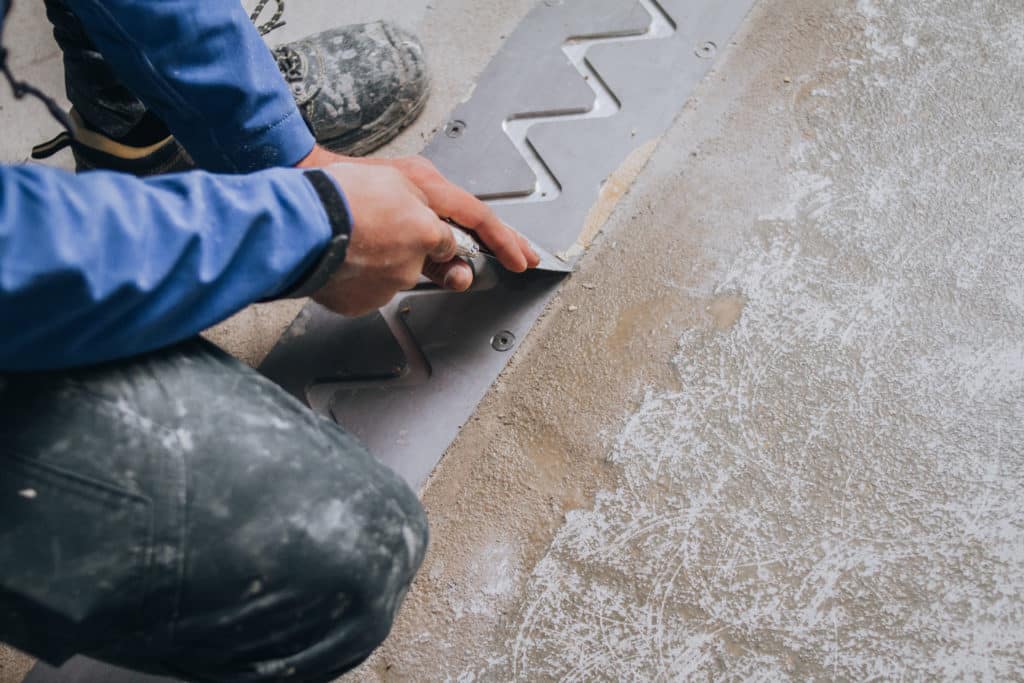 Worker caulking for waterproofing installation.