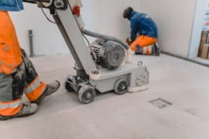 Construction workers using floor saw indoors.