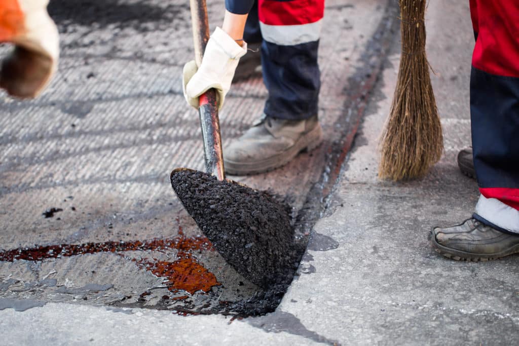 Workers patching asphalt on road.